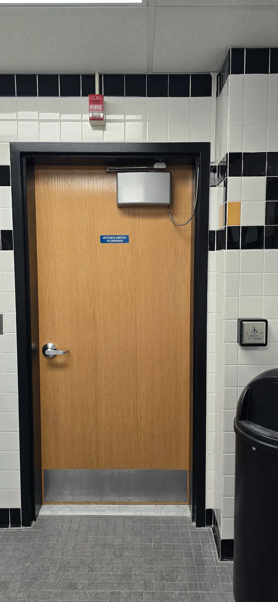 Overhead ADA automatic operator and wall push plate above a commercial fire door