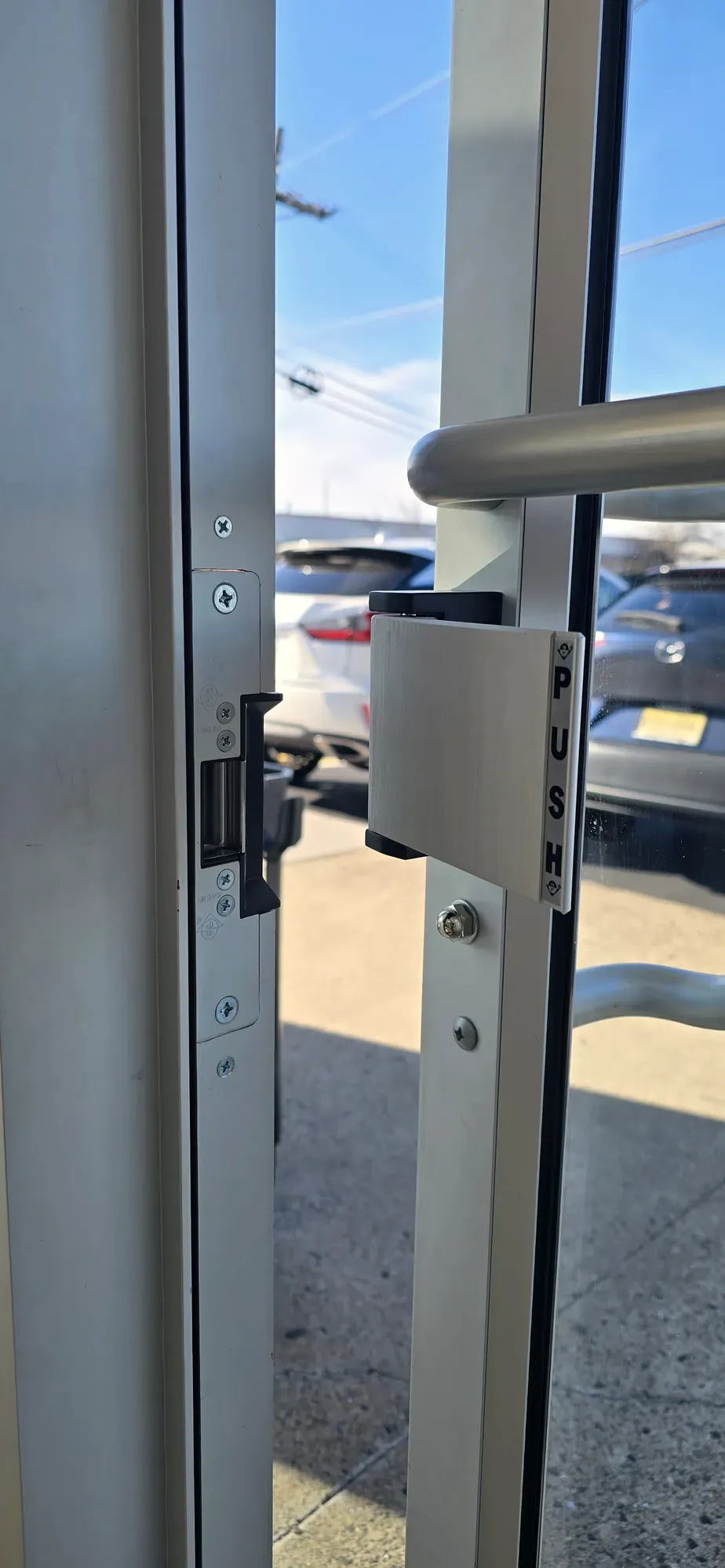Push paddle and electric strike on an aluminum entry door